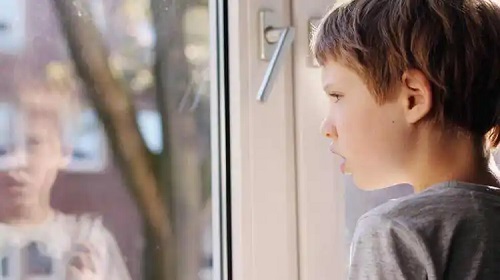 Copil autist uitându-se pe geam