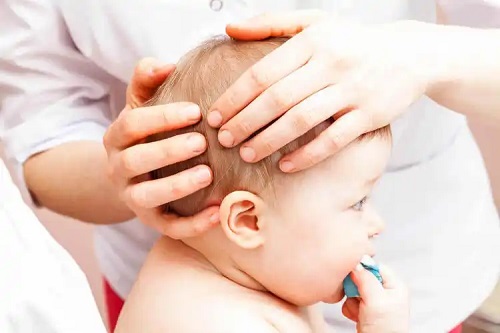 Medic care examinează fontanela la bebeluși