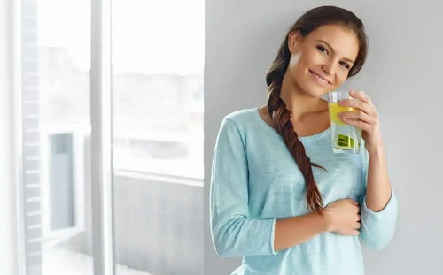 Femeie care bea apă de semințe de in pentru combaterea celulitei