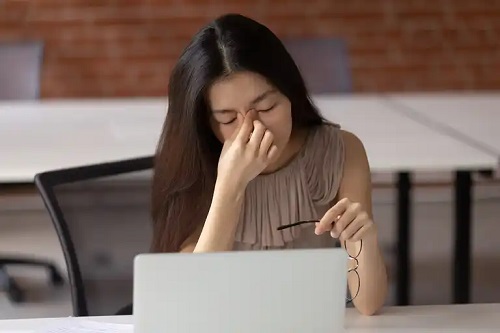 Femeie care se confruntă cu problemele de vedere în telemuncă