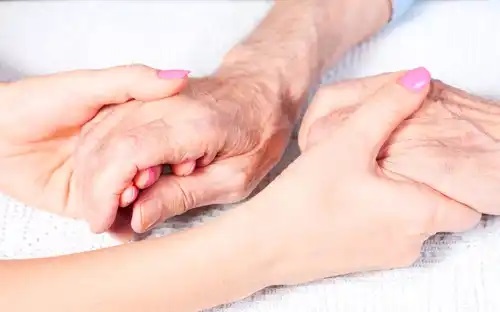 Voluntar care ține de mână un bătrân