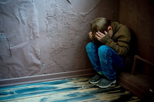 Copil speriat într-un colț al camerei