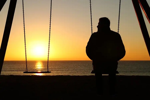 Bărbat melancolic în leagăn pe plajă