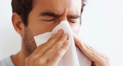 Bărbat care își suflă nasul