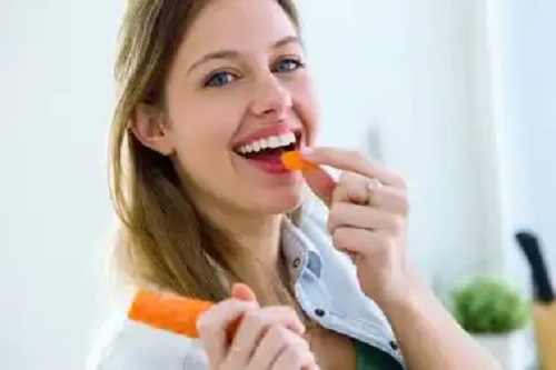 Femeie care mănâncă morcovi
