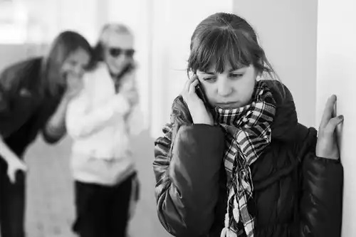Adolescenți care râd de alt copil