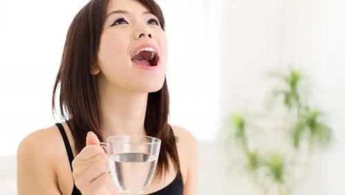 Femeie care face gargară cu bicarbonat de sodiu