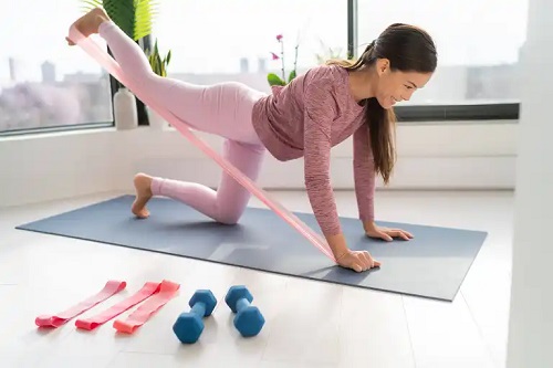 Femeie care face exerciții pentru fesieri cu benzi de rezistență
