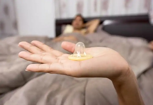 Femeie care ține în mână un prezervativ