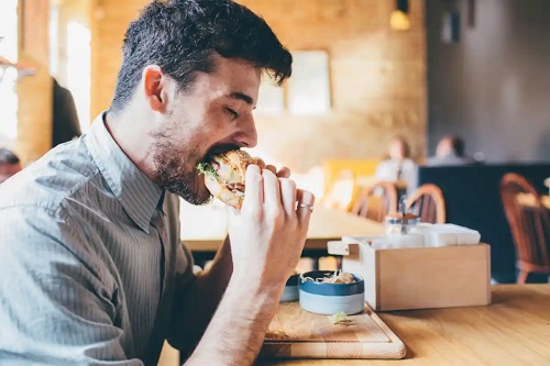 Bărbat care mănâncă un burger
