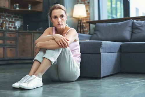 Femeie apatică stând pe podea