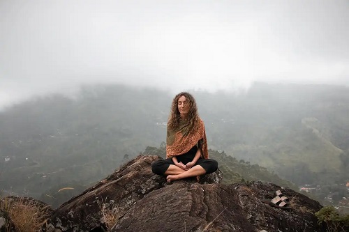 Femeie care meditează la munte