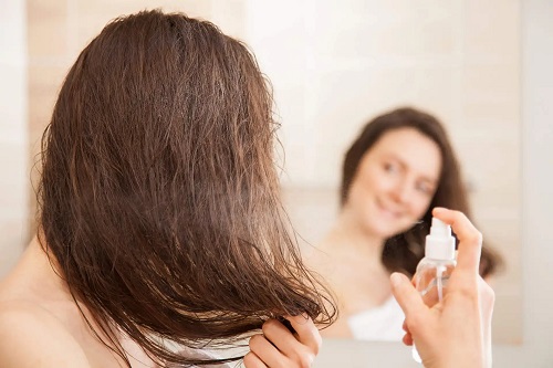 Femeie ce folosește spray cu vitamina B5 bună pentru păr