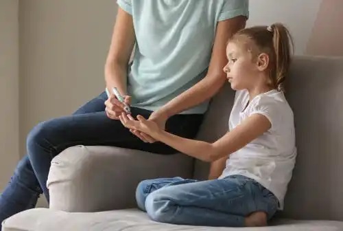 Mamă care măsoară glicemia copilului