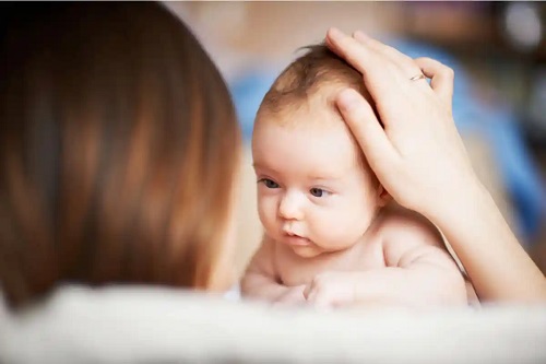 Mamă care verfică părul bebelușului