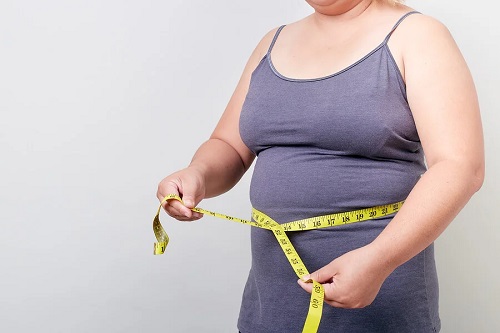Persoană obeză care își măsoară talia
