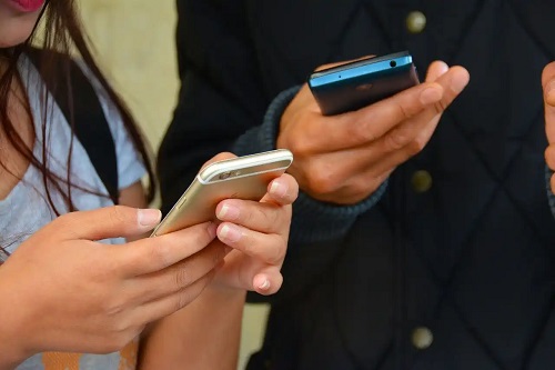Tineri care butonează telefoanele mobile
