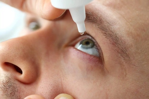 Bărbat care folosește lacrimile artificiale pentru ochii uscați