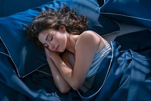 Femeie care doarme în așternuturi albastre