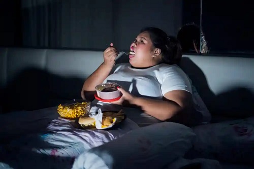 Femeie obeză care mănâncă noaptea