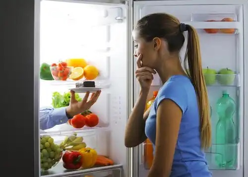 Femeie care caută mâncare în frigider