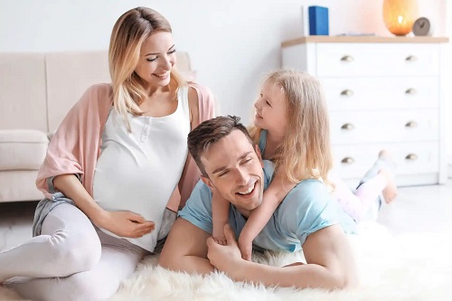 Femeie gravidă alături de familie