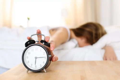 Femeie care oprește alarma ceasului dimineața