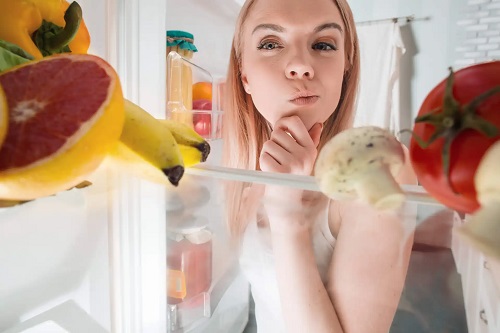 Femeie care se uită în frigider