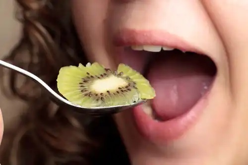 Femeie care consumă kiwi