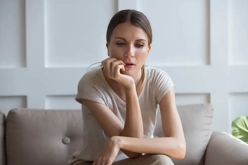 Femeie gânditoare pe canapea